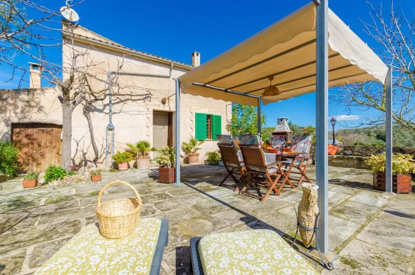 A sunny stone patio with outdoor seating beneath a fabric canopy.