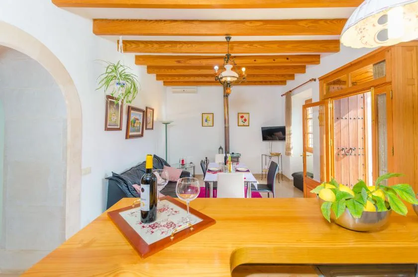 A dining area with a wooden table, colorful chairs, and exposed ceiling beams.