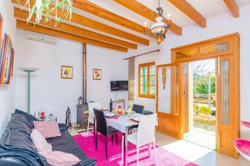 A living and dining area with a table, seating, and open doors to a patio.