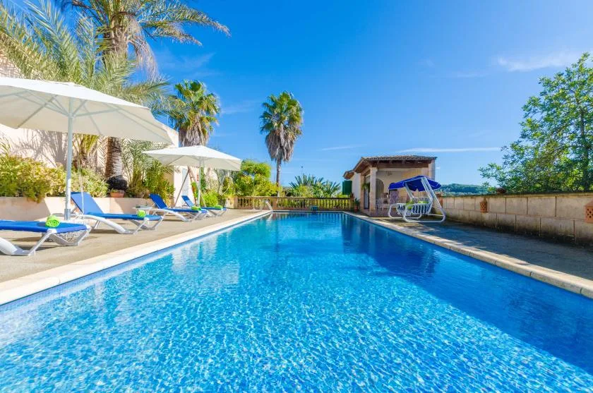 An outdoor swimming pool with lounge seating and umbrellas along the side.