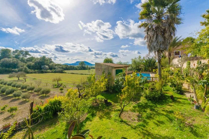 A landscaped garden surrounds a small building, with open countryside beyond.