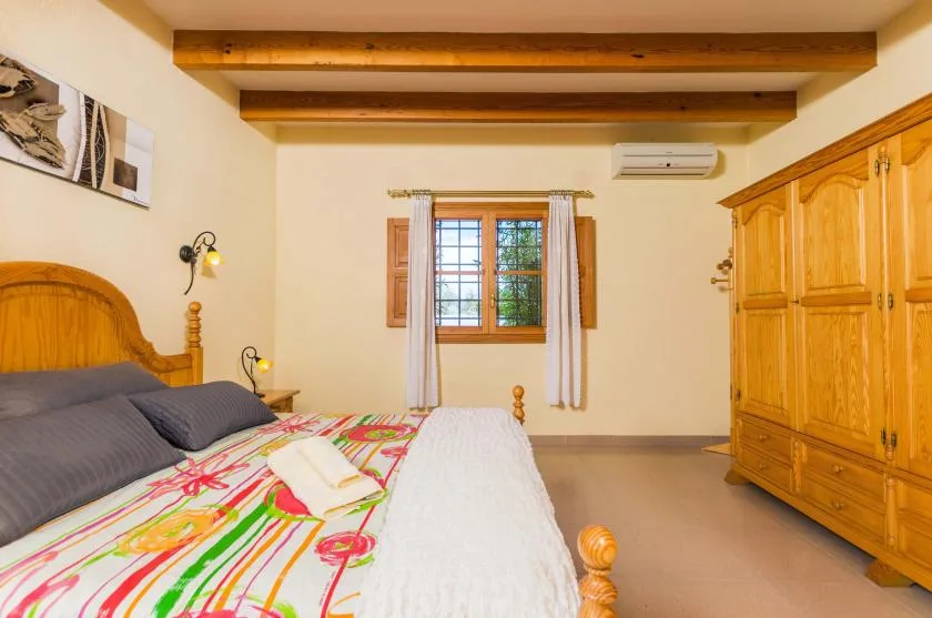 A bedroom with a wooden bed, colorful bedding, and a large wardrobe.