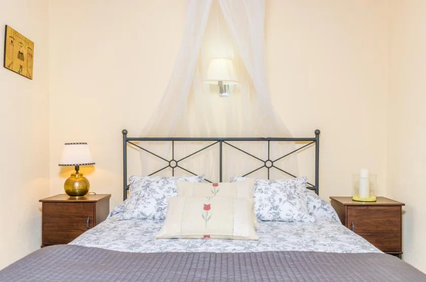 A bedroom with a bed, patterned pillows, and matching bedside tables.