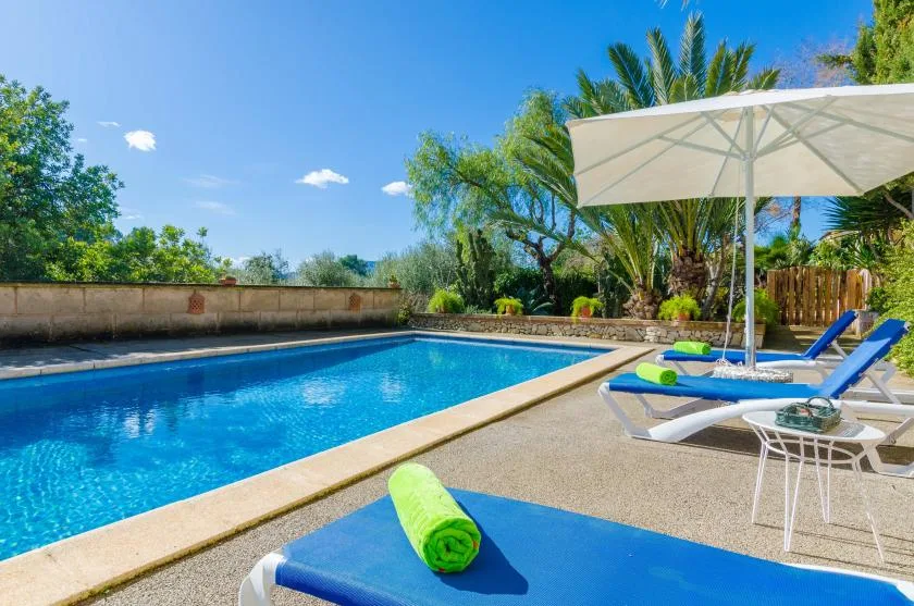 An outdoor swimming pool with loungers and a large shade umbrella.