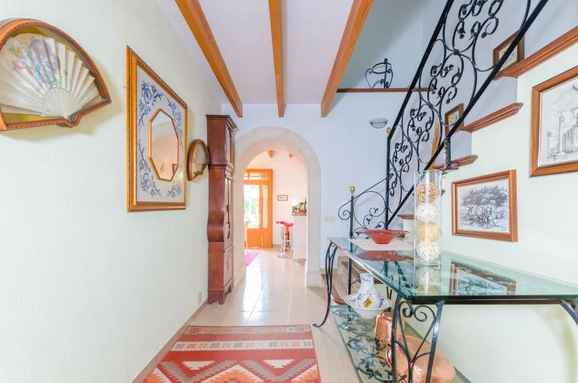 A bright interior hallway with a staircase and framed wall art.