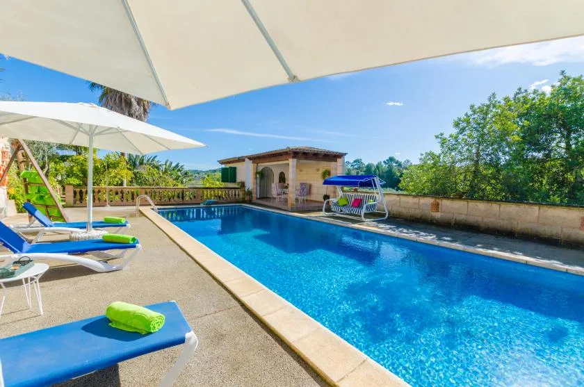 An outdoor swimming pool with lounge seating beneath large umbrellas.