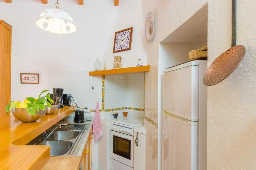 A compact kitchen with wooden counters, a sink, and a refrigerator.