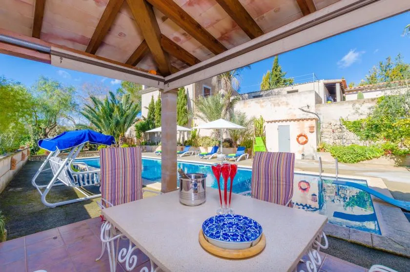 A covered patio dining area overlooks a swimming pool and landscaped garden.