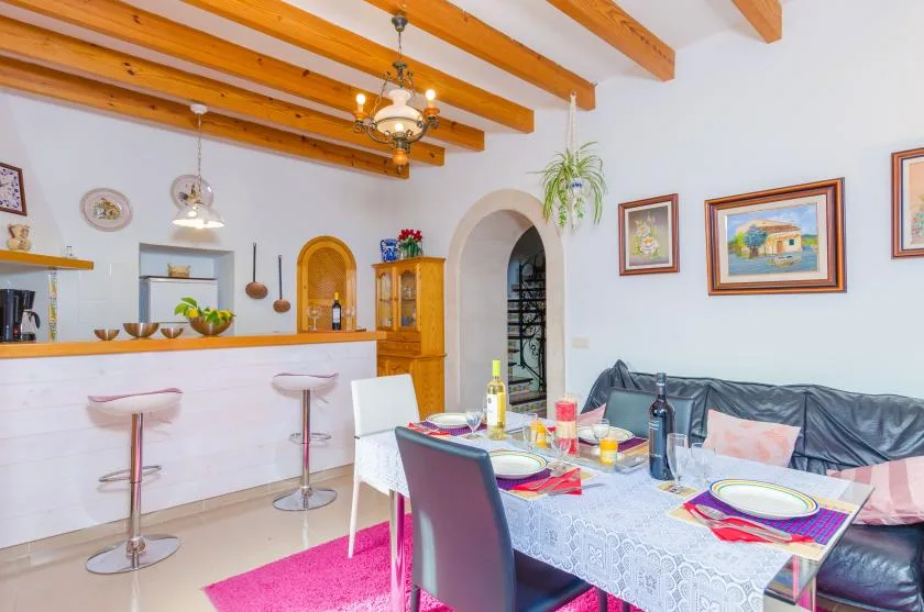 A dining area with a set table beside a kitchen counter and bar seating.