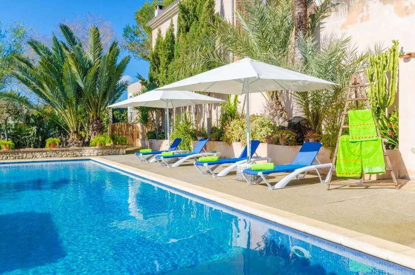 An outdoor swimming pool beside lounge seating and shaded umbrellas.
