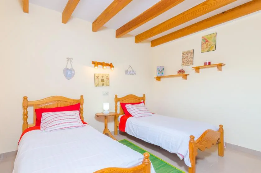 A bedroom with two single beds, white bedding, and exposed ceiling beams.