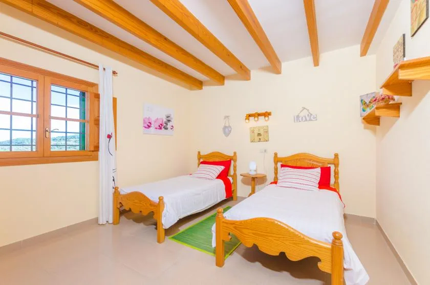 A bedroom with two wooden beds, white bedding, and a window.