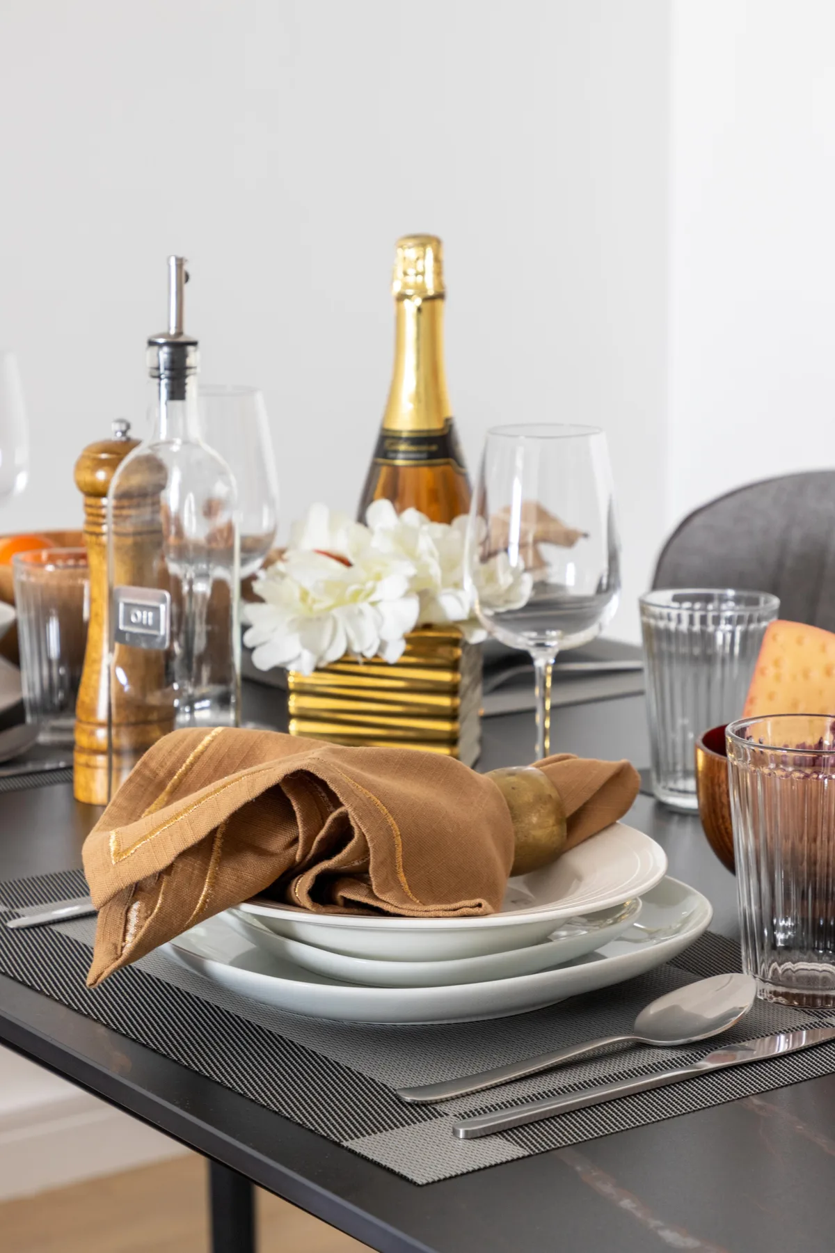 Una mesa de comedor está puesta con platos, servilletas dobladas, cristalería y flores.