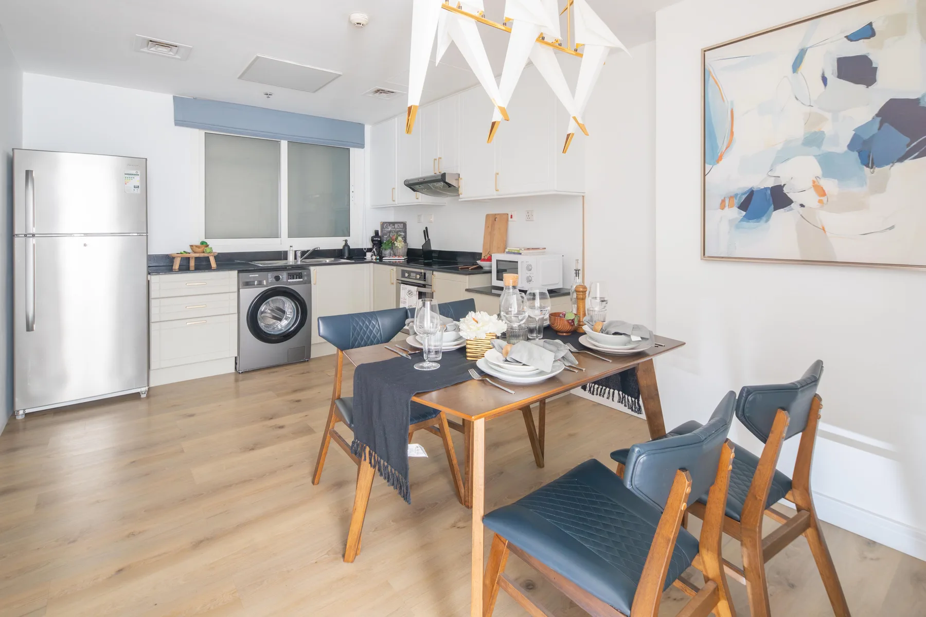 Comedor con la mesa puesta junto a una cocina compacta.