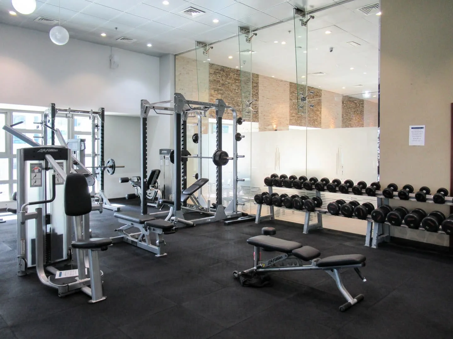 Un gimnasio con máquinas de pesas, mancuernas y bancos de ejercicio.