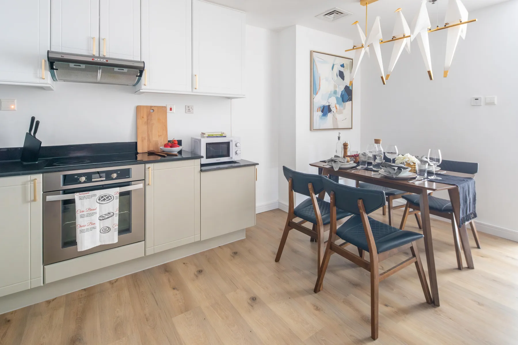 Una cocina luminosa y zona de comedor con una mesa puesta junto a las encimeras.