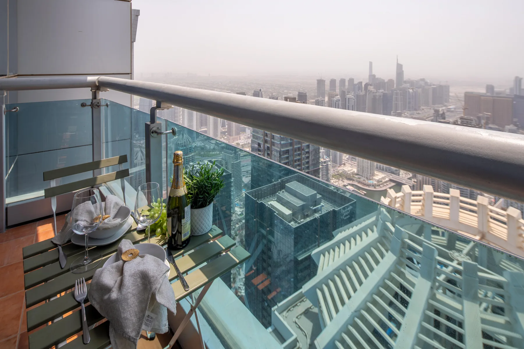 Una zona de comedor en el balcón da a un horizonte urbano brumoso.