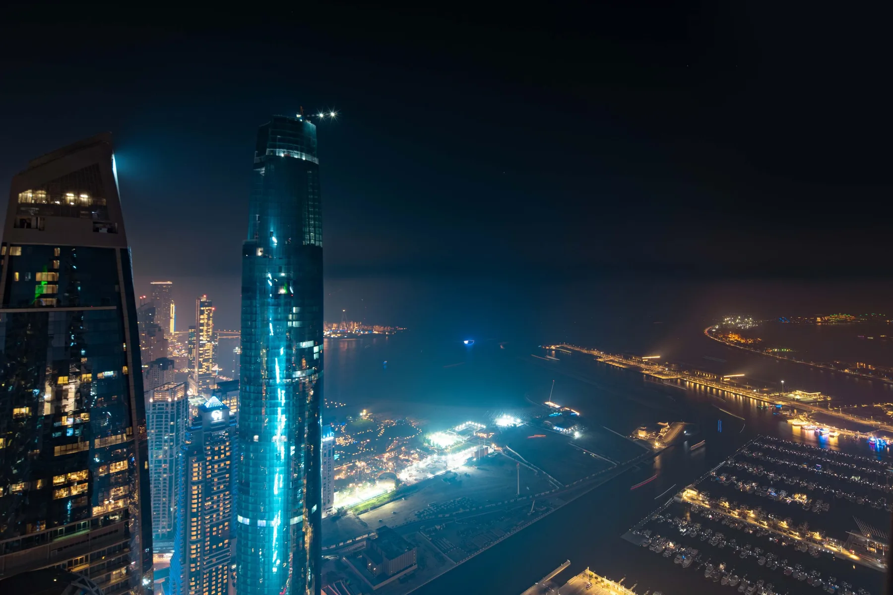 Panorámica nocturna de la ciudad con edificios altos y carreteras iluminadas.