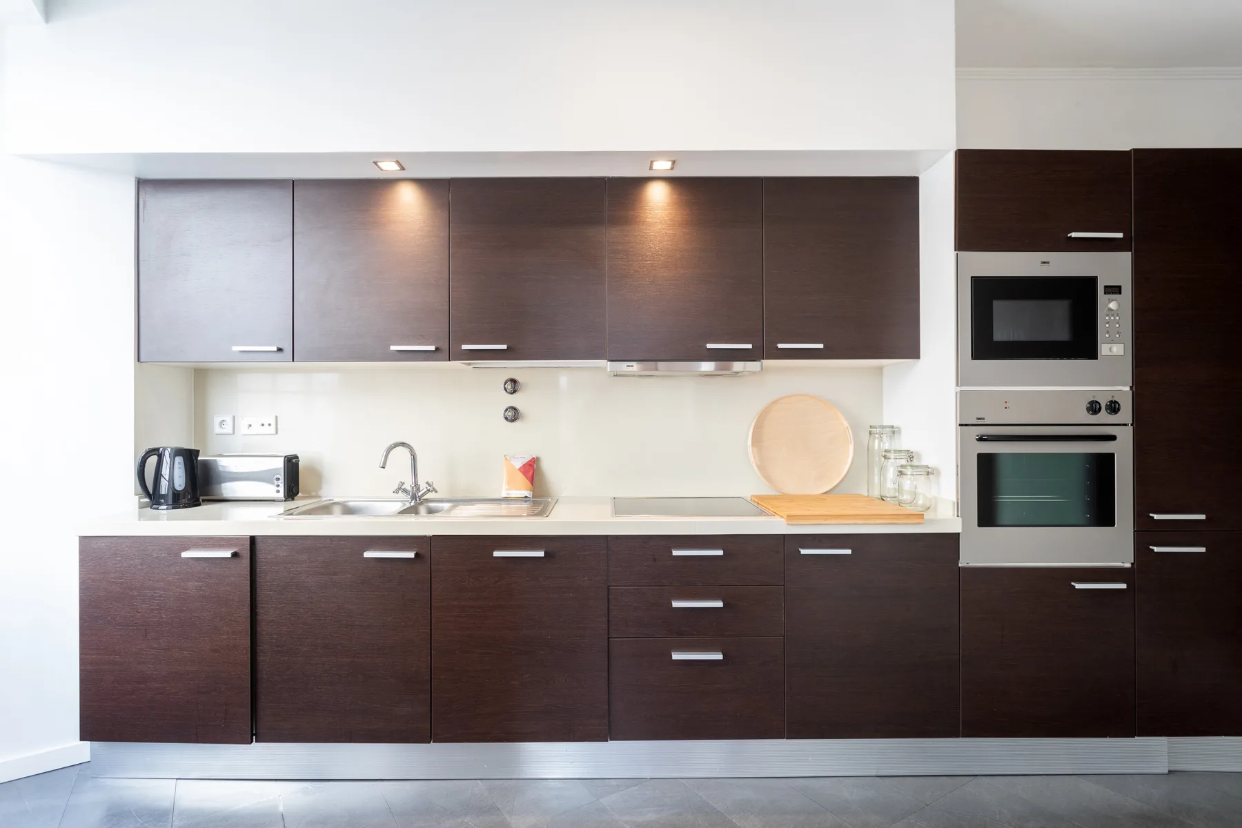 Una cocina moderna con gabinetes oscuros, una encimera y electrodomésticos empotrados.