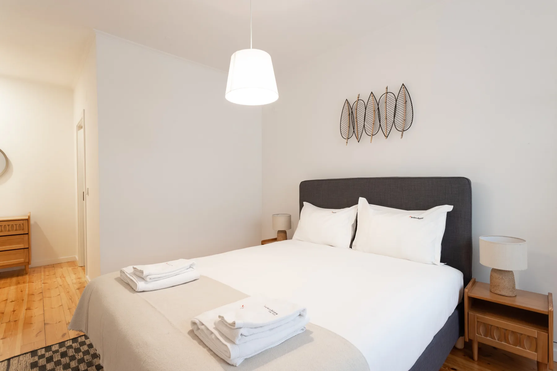 A bright bedroom with a large bed and folded towels.