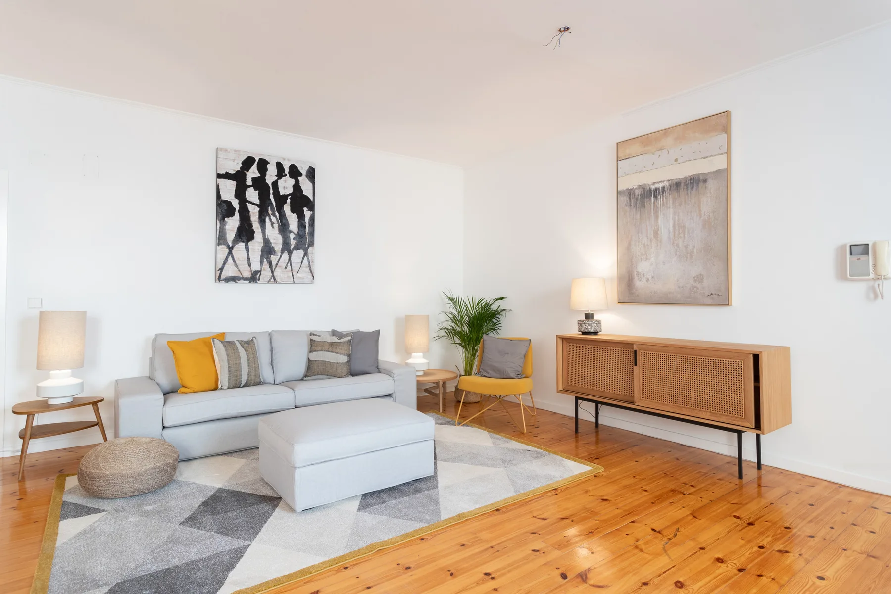 A bright living room with seating, a coffee table, and wall art.