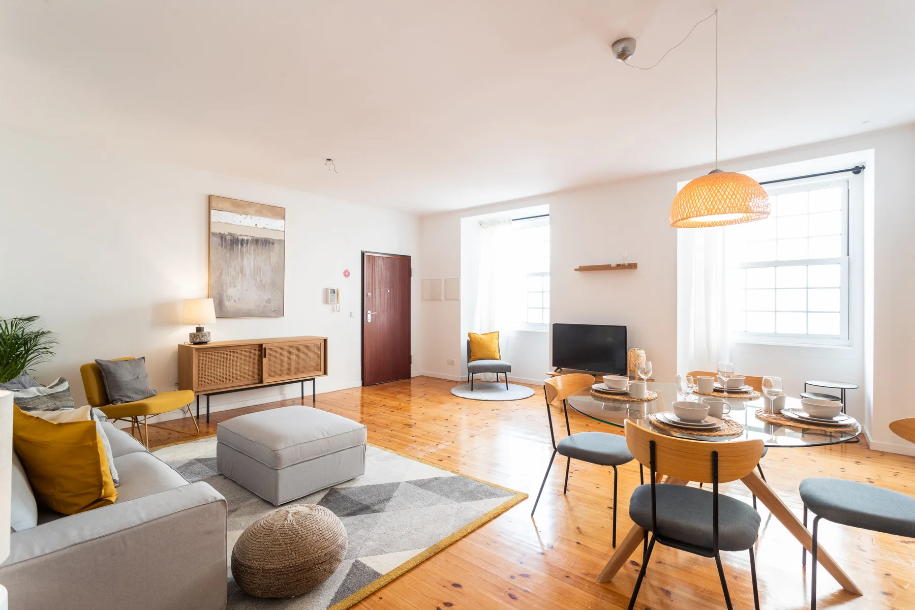 Bright living and dining area with seating, a television, and large windows.