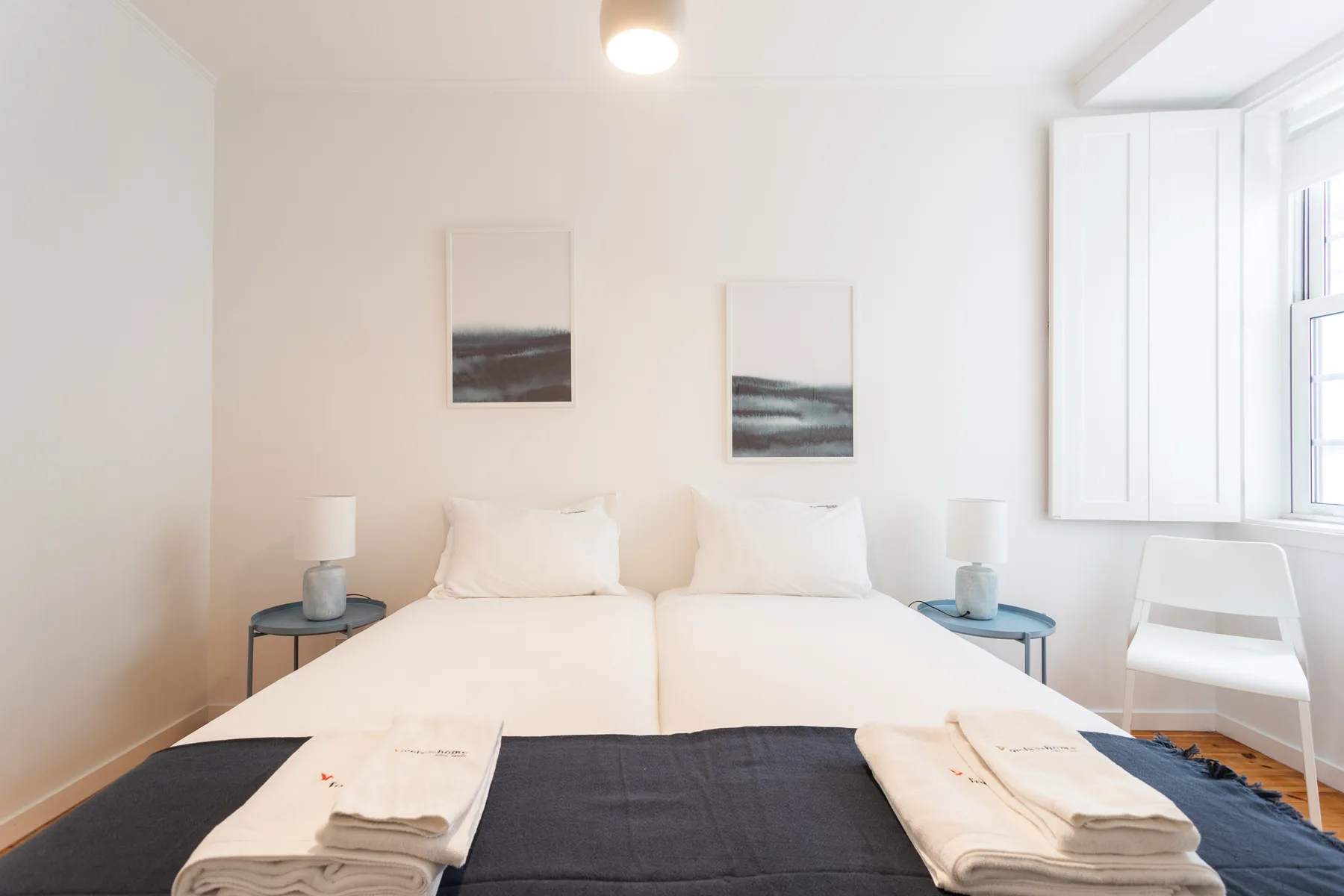 Un dormitorio luminoso con dos camas y cuadros en la pared.