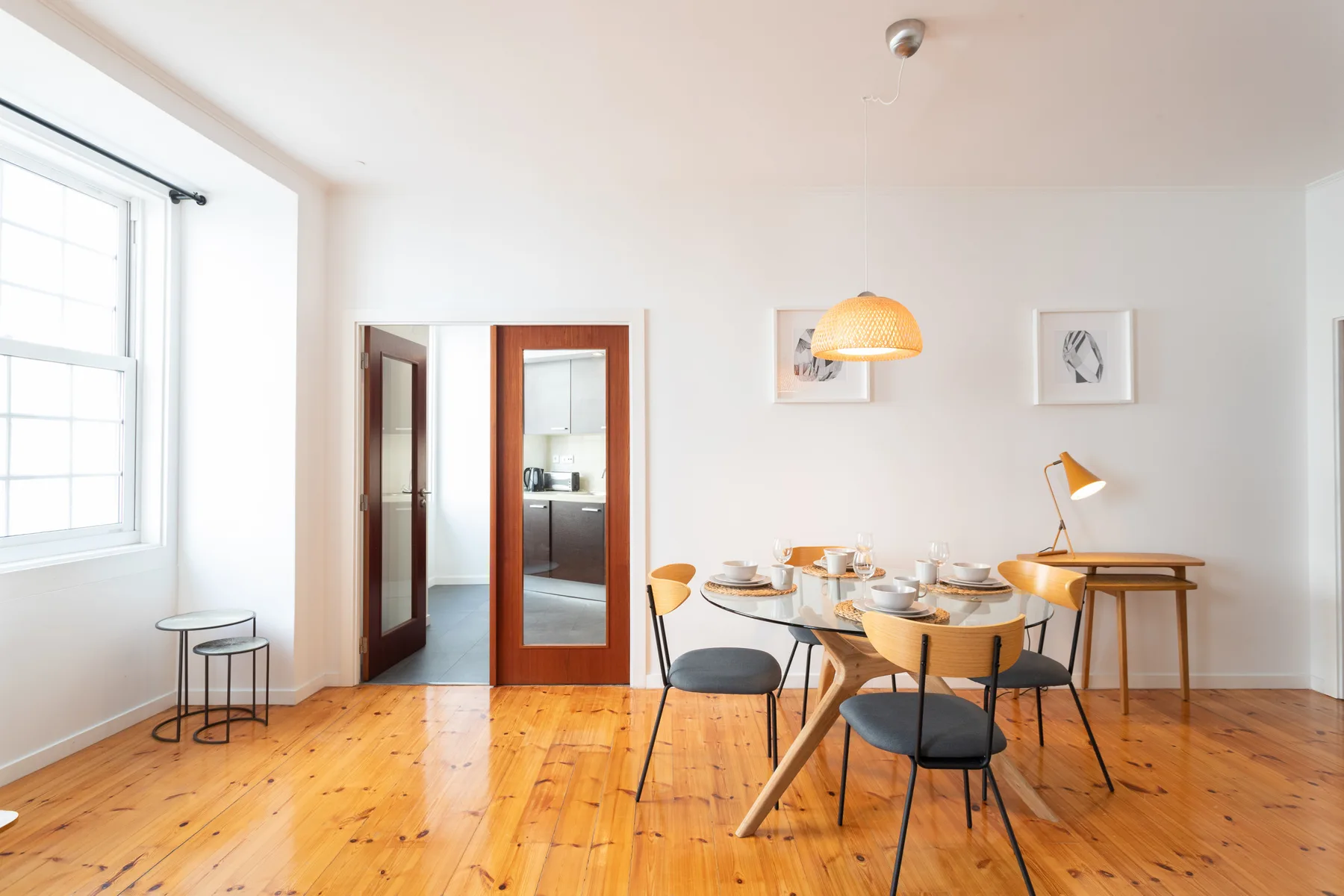 A bright dining area with a table and chairs beside large windows.