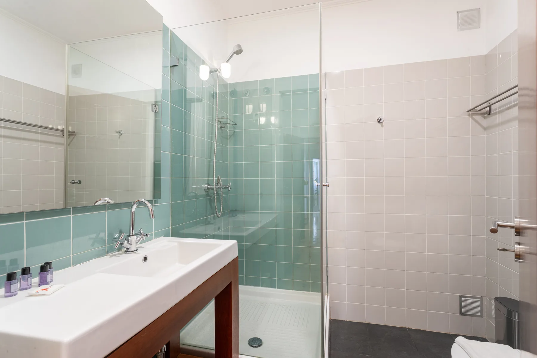 A tiled bathroom with a sink, mirror, and glass-enclosed shower.