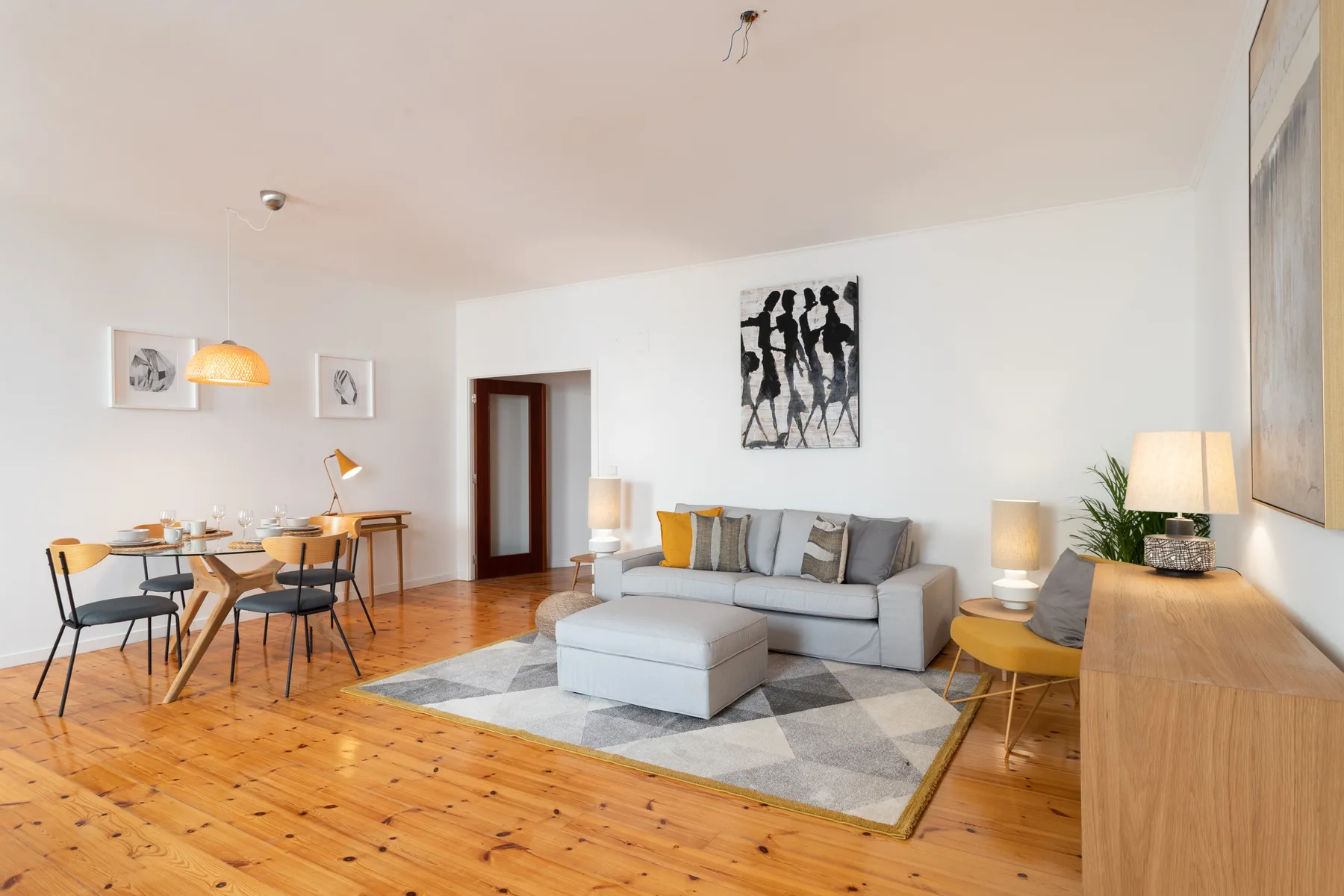 A bright living and dining room with seating, a table, and wood flooring.