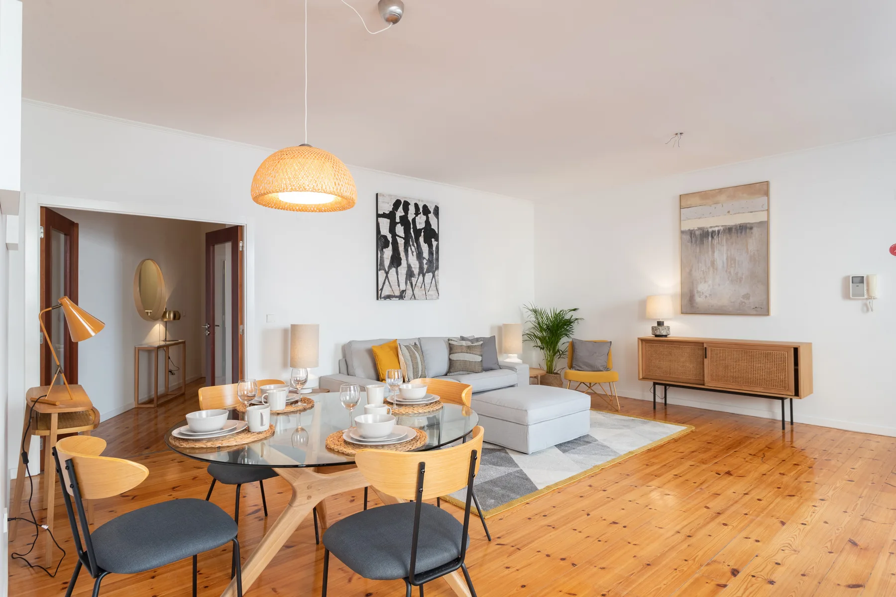 A bright living and dining room with seating around a glass dining table.