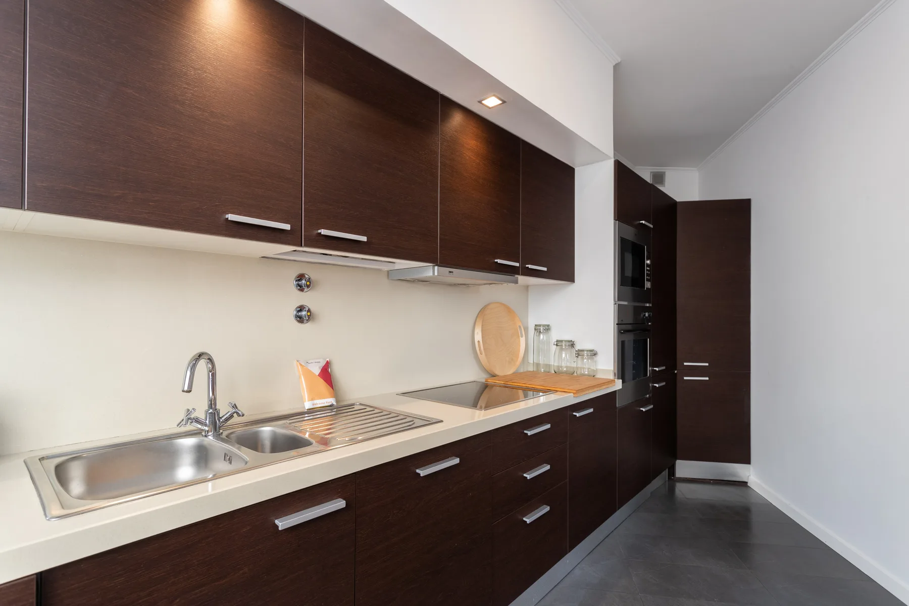 Una cocina moderna con gabinetes oscuros, un fregadero y una encimera.