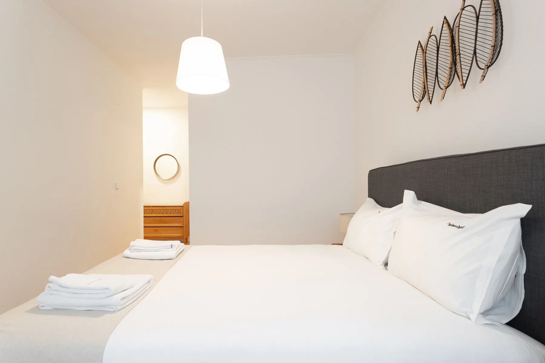 Un dormitorio luminoso con una cama bien tendida y toallas dobladas.
