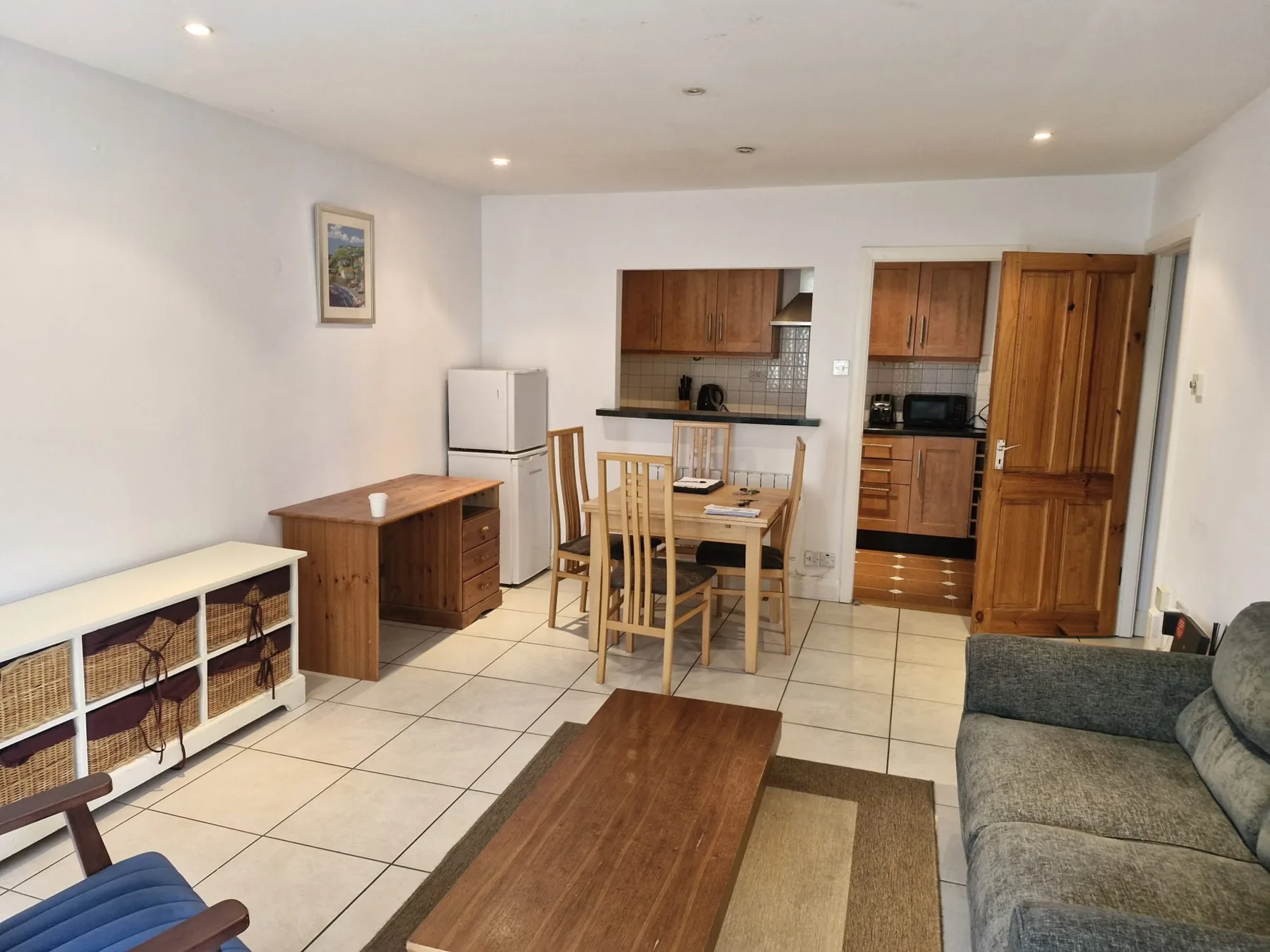 Sala de estar y comedor con una mesa de madera y una cocina abierta.