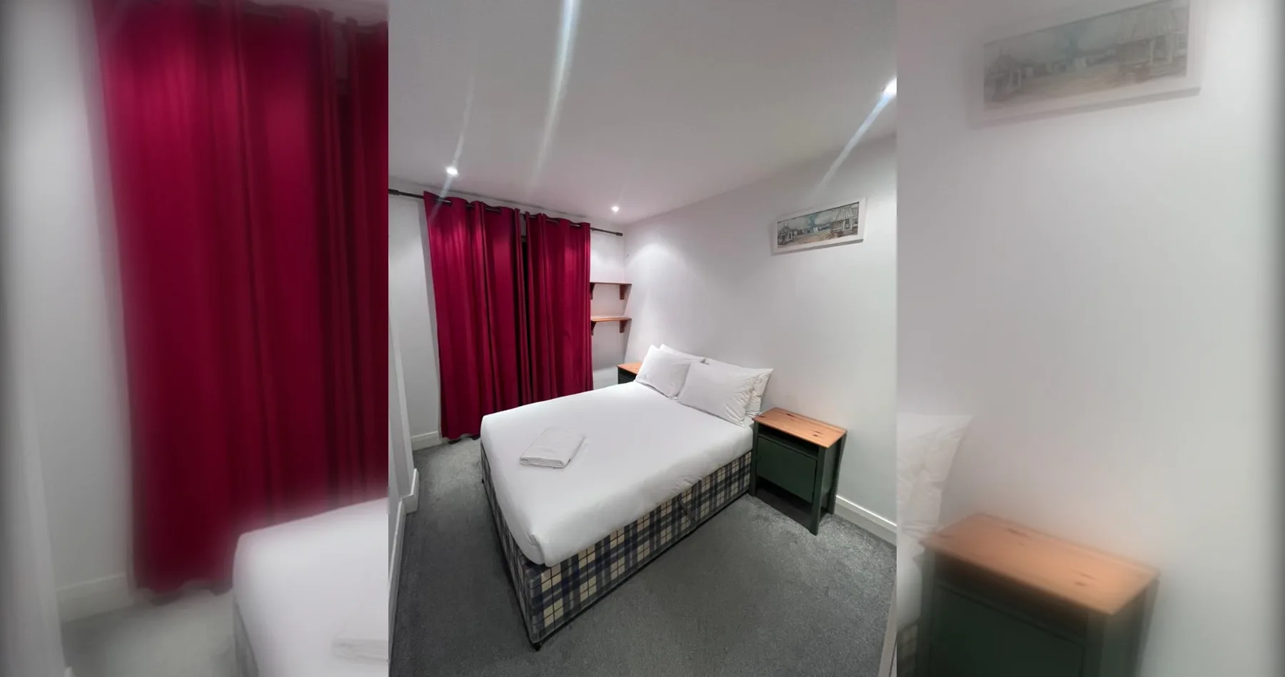 Un dormitorio con una cama, cortinas rojas y una pequeña mesa de noche.