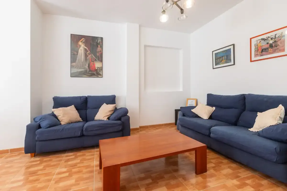 Una sala de estar con asientos azules y una mesa de centro de madera.