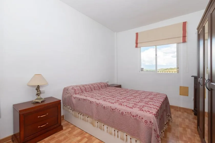 Un dormitorio con una cama cubierta con una colcha estampada junto a una ventana.