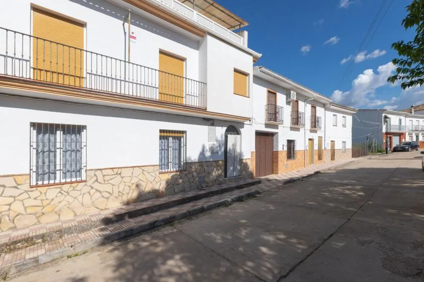 Una hilera de edificios residenciales blancos con balcones junto a una calle pavimentada.