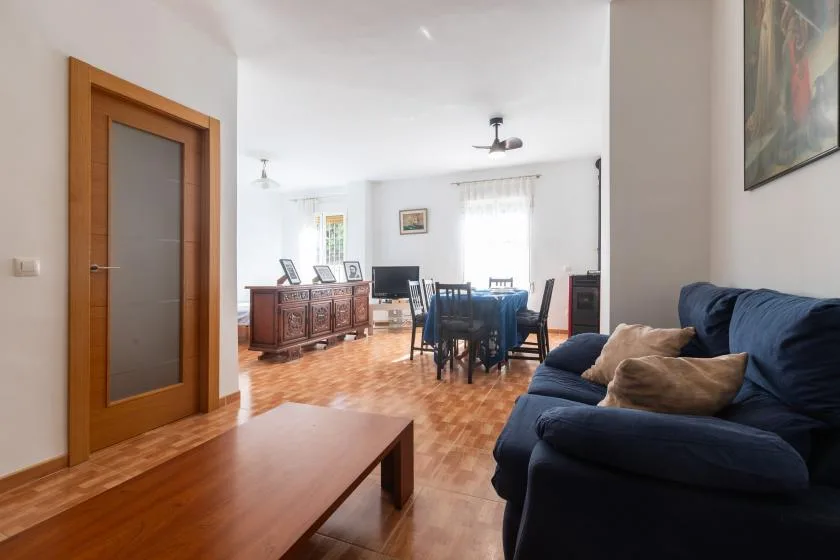 Un salón-comedor luminoso con una mesa de centro de madera y asientos azules.