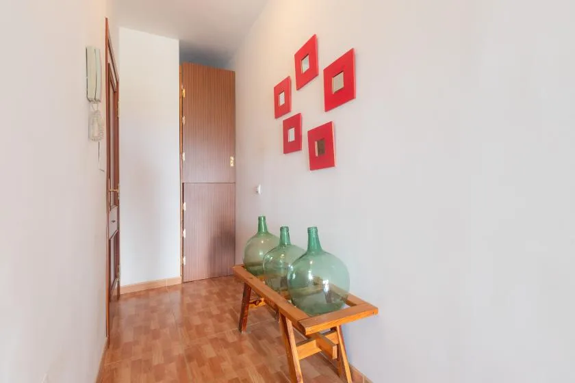Un pasillo con una mesa consola de madera y adornos rojos en la pared.