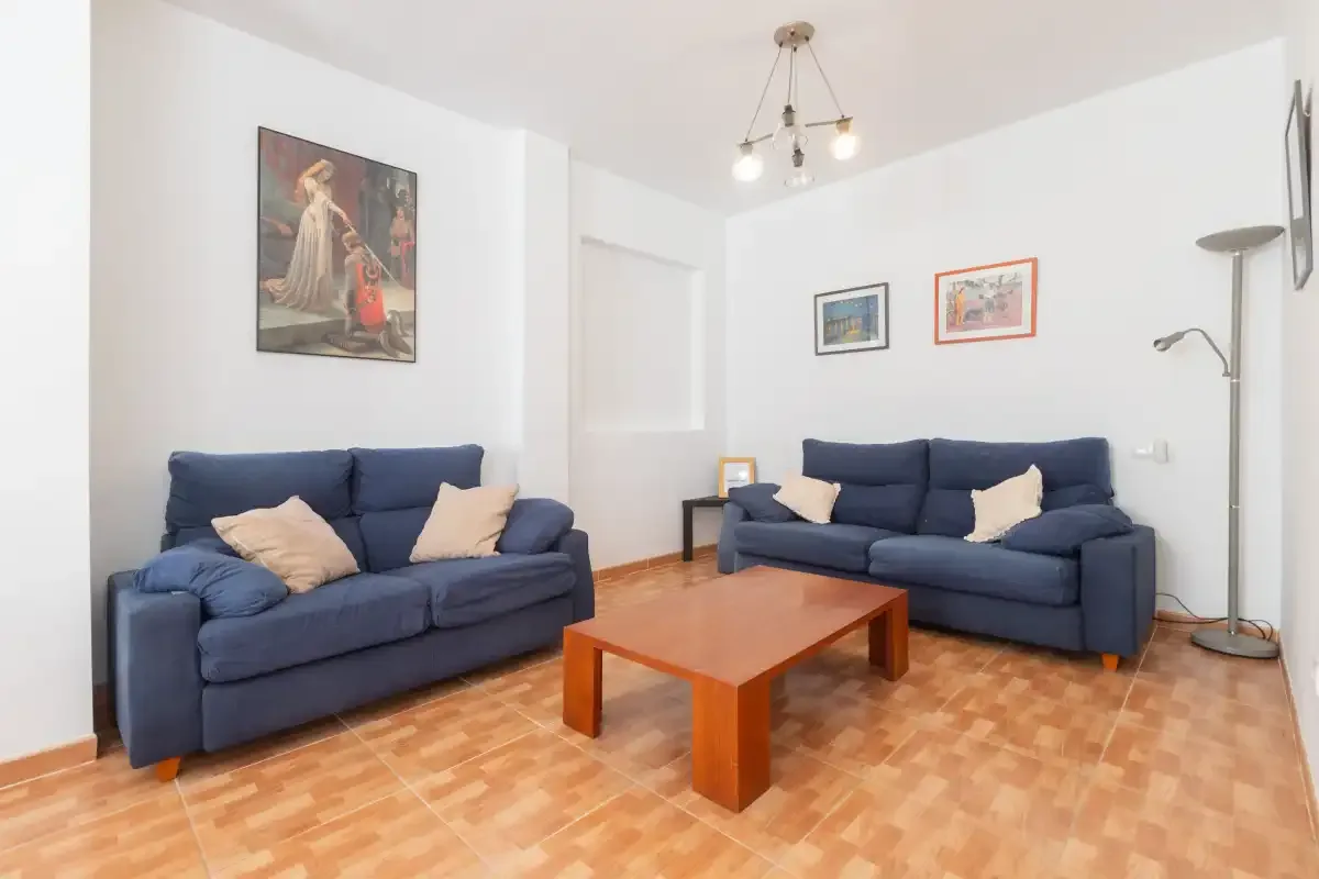 Una sala de estar con asientos azules alrededor de una mesa de centro de madera.