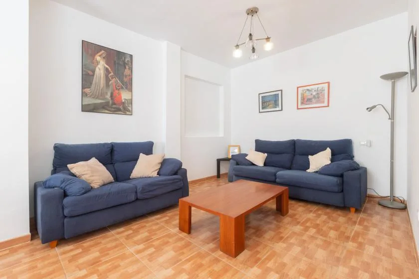 Una sala de estar con asientos azules y una mesa de centro de madera.