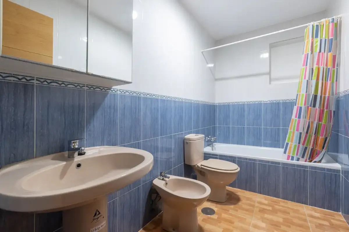 Un baño con bañera, lavabo, inodoro y una cortina de ducha colorida.