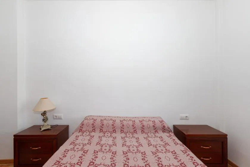 Un dormitorio con una colcha estampada y mesitas de noche de madera a juego.