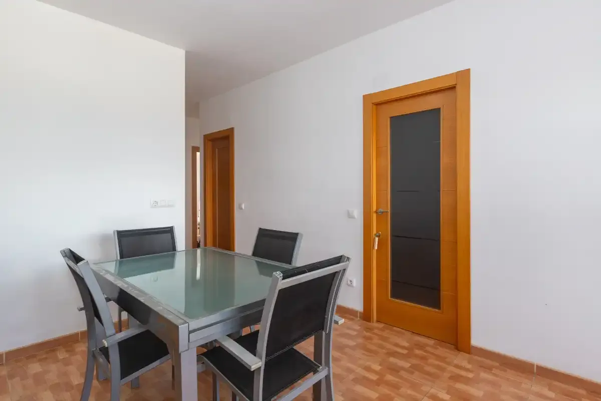 Comedor con mesa de vidrio y asientos oscuros.