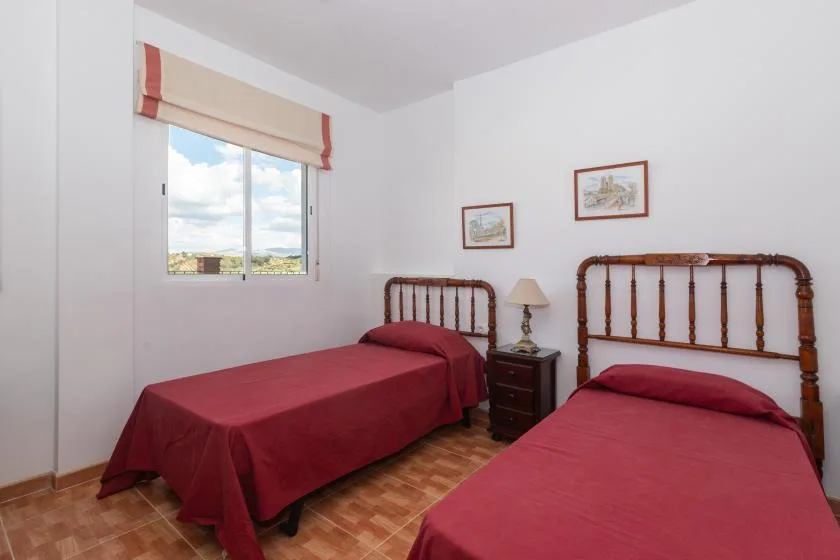 Un dormitorio con dos camas, una mesita de noche y una ventana.