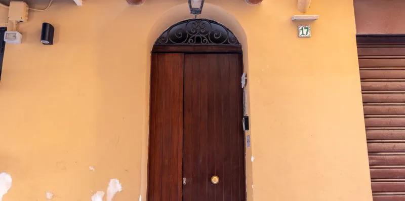 An arched wooden doorway set into a yellow exterior wall.
