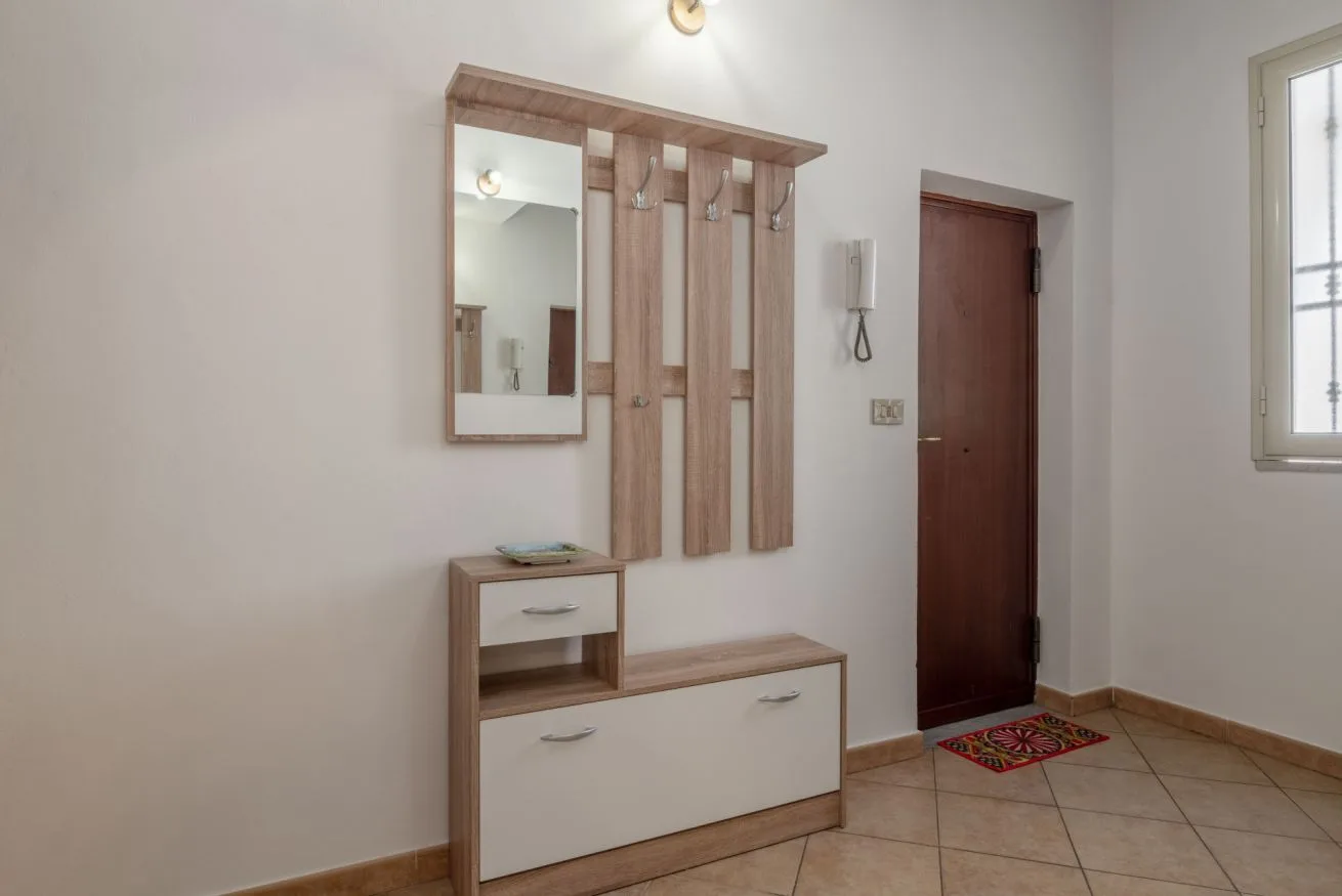 An entryway with a wall-mounted mirror and a small storage bench.