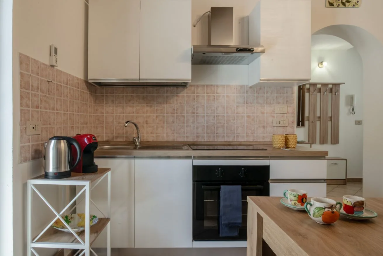 A compact kitchen with a tiled backsplash, countertop, and built-in oven.