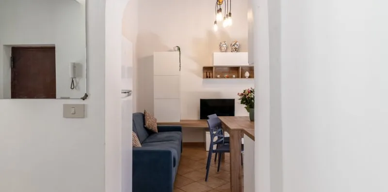 Una zona de comedor y estar con mesa, sillas y asientos azules.